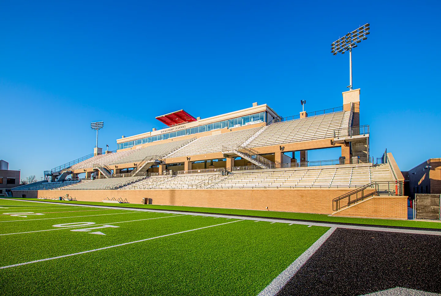 The red metal panels that wrap the structural framing for the camera deck pay homage to the iconic light fixtures of the former stadium.